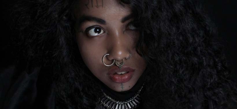Portrait rapproché mettant en valeur piercings et tatouages du visage